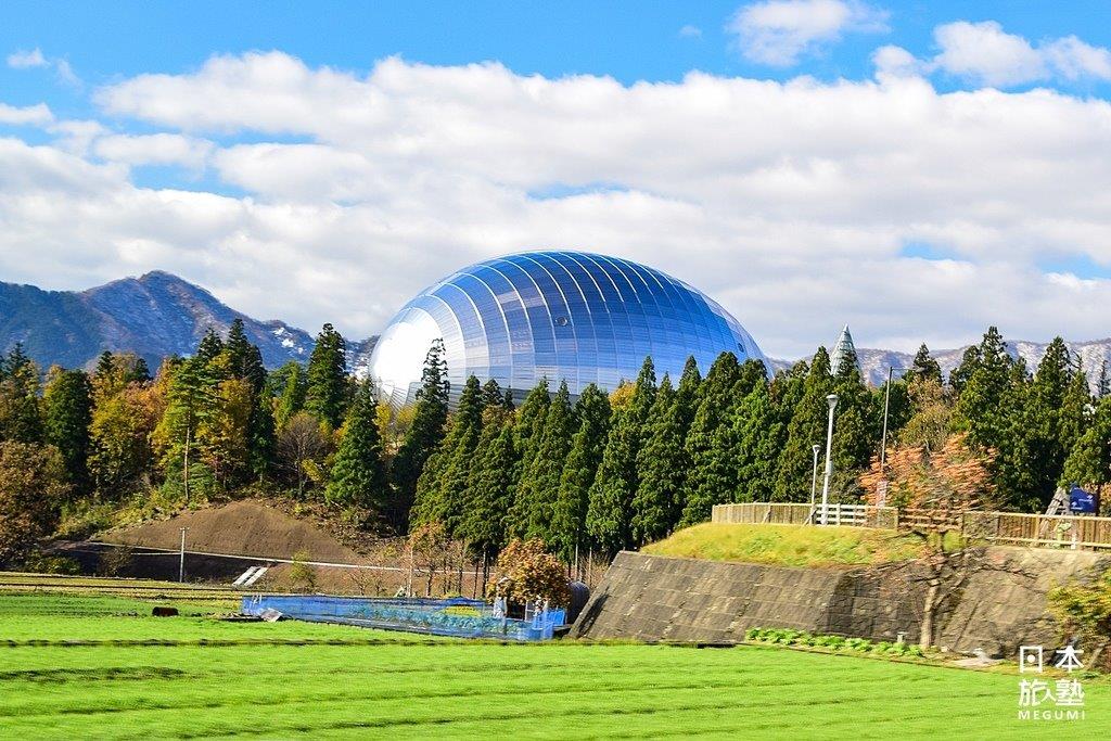 由附近的田間往博物館方向望去，建築造型彷彿一顆巨大的恐龍蛋