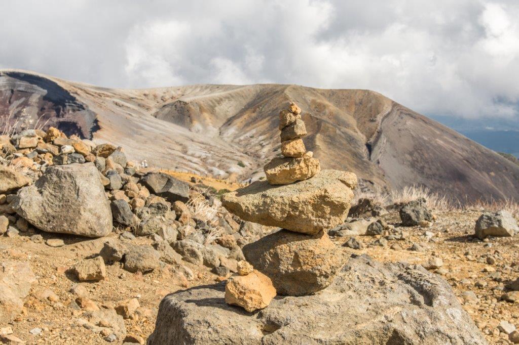 畢竟是火山地，路上岩石不斷，幸好旅行時總習慣穿著好走的鞋子，才能在這黃沙土中輕鬆行走，不受影響，一路在岩石上見到了登山人堆疊的石頭，想起了去年六月在北海道旭岳火山登山時也見同樣的景色。