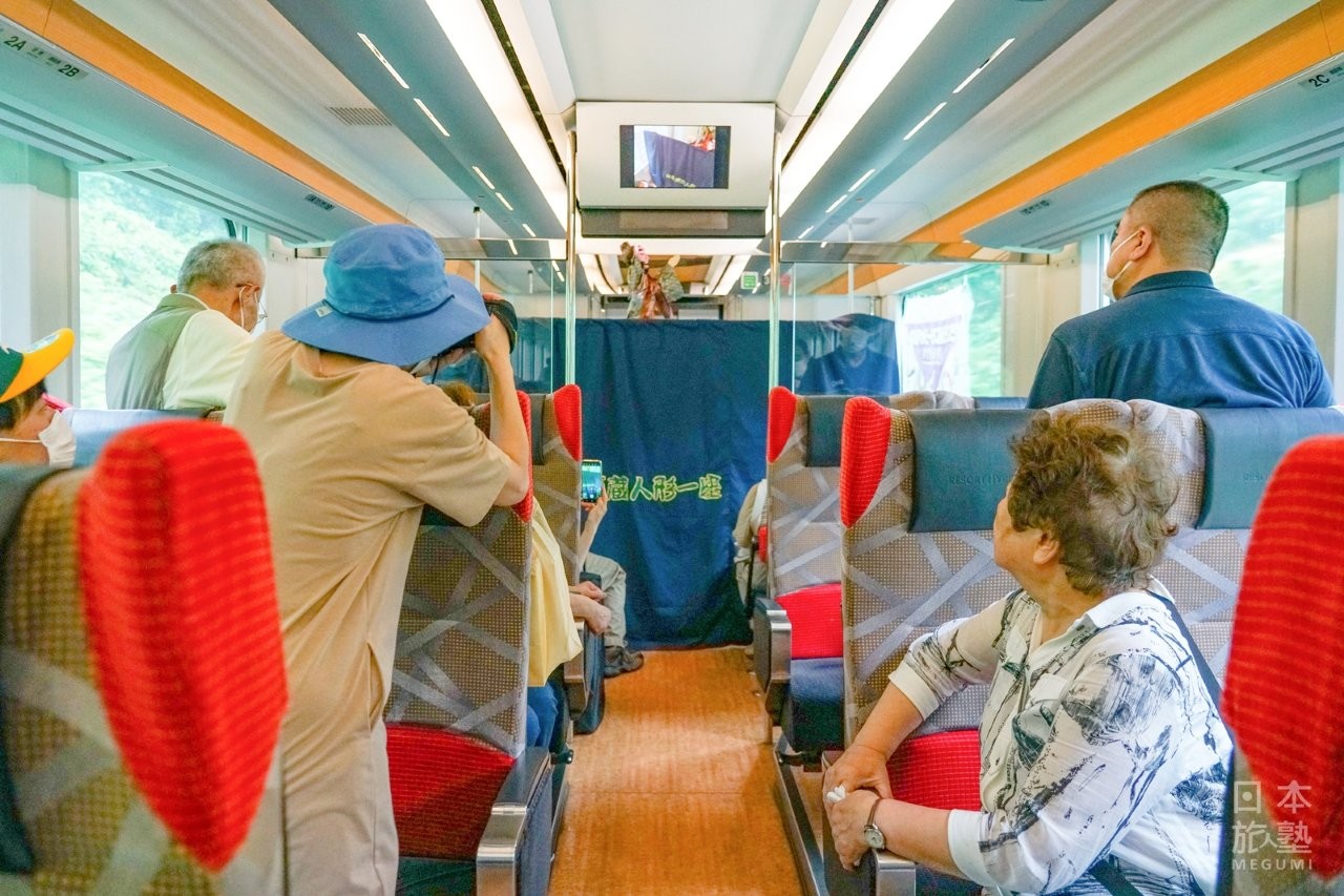 乘客聚精會神地欣賞車內的偶劇表演