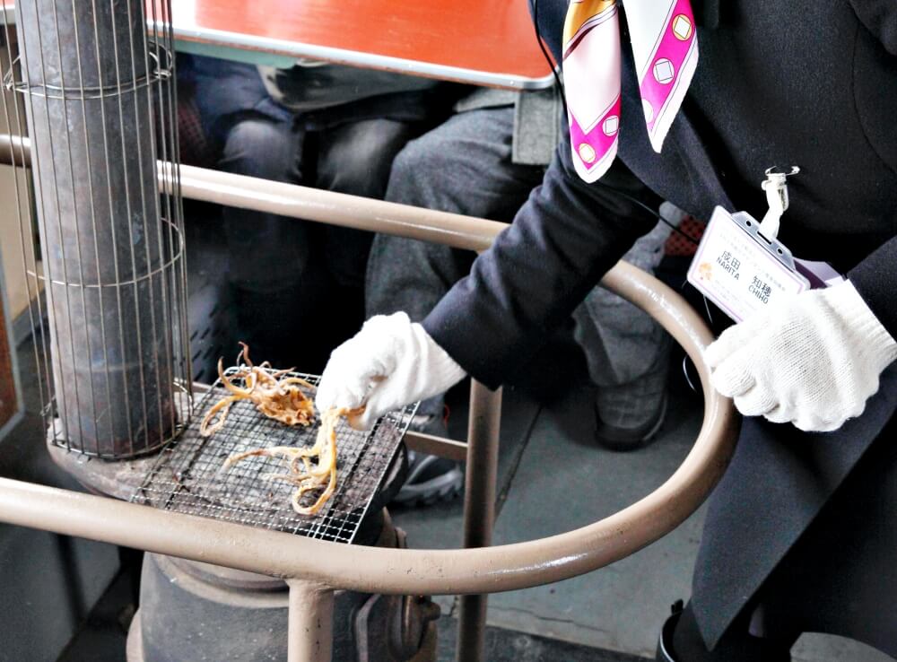乘務員在爐子上加熱魷魚。(Image credit: 青森県観光連盟)
